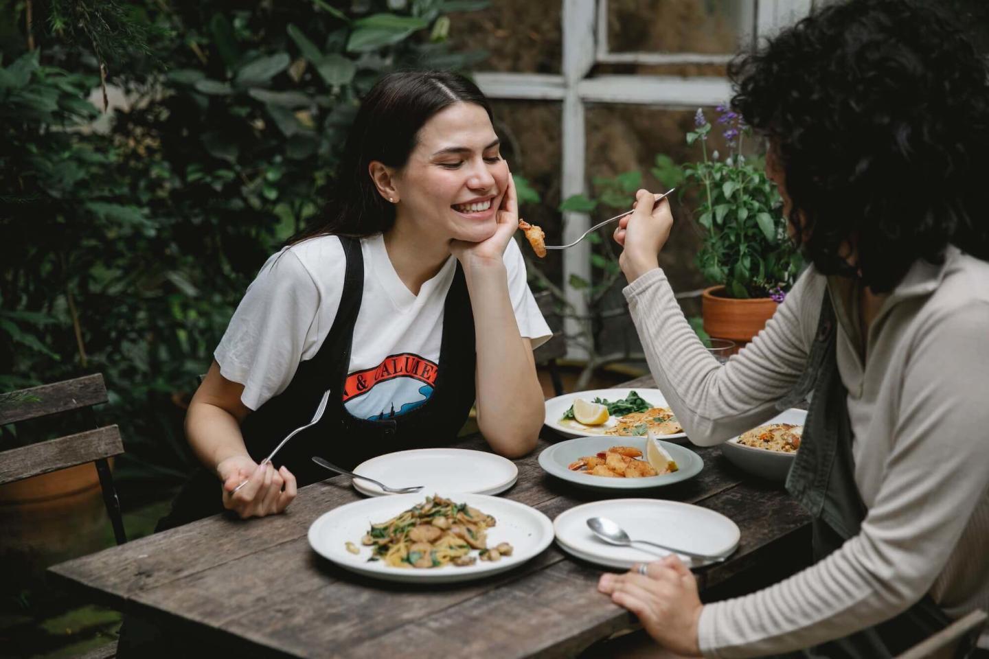 Two women eating, one feeding the other